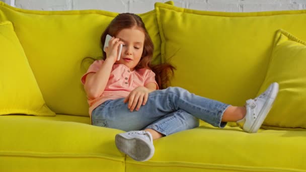очаровательный ребенок разговаривает на смартфоне и расслабляется на диване
 - Кадры, видео