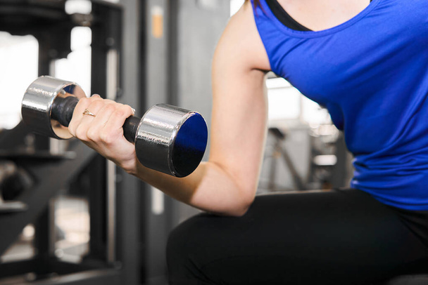 ruka ženy provádějící činka cvičení pro biceps v tělocvičně - Fotografie, Obrázek