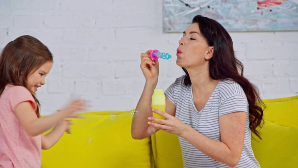 mère heureuse soufflant des bulles de savon près de la fille
  - Séquence, vidéo