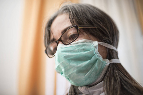 Ιός Κορόνα. Άρρωστη γυναίκα από τον ιό Κορόνα φορώντας προστασία αναπνοής και ανάρρωση από την ασθένεια στο σπίτι. Ασθενής απομονωμένος για πρόληψη λοίμωξης - Φωτογραφία, εικόνα