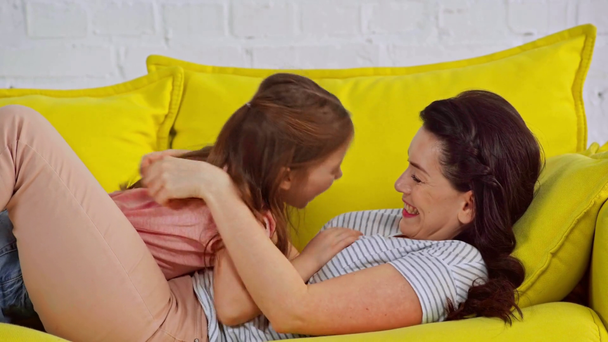 χαριτωμένο παιδί γαργαλάει ευτυχισμένη μητέρα στο σαλόνι  - Πλάνα, βίντεο