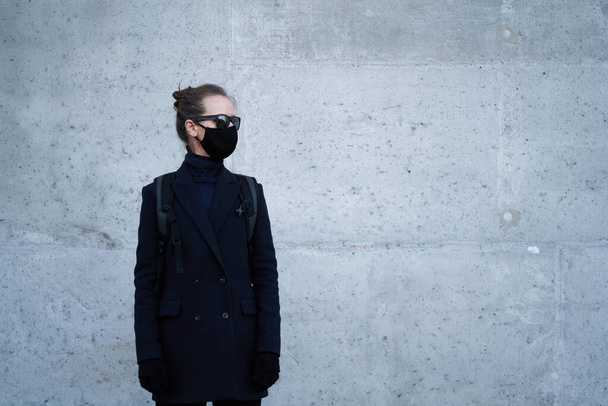 Young girl in a black protective mask and black sunglasses on the street, protecting against the virus - Foto, immagini