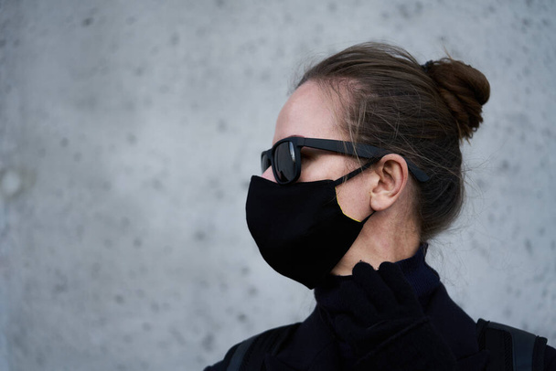 Young girl in a black protective mask and black sunglasses on the street, protecting against the virus - Foto, Imagem