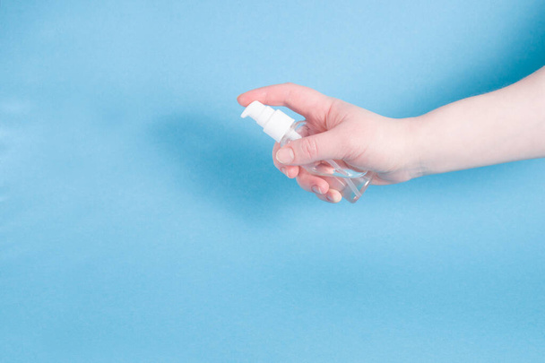 Female hand holds a sanitizer on the palm, personal hygiene concept, protection against coronavirus, stop coronavirus, blue background, copy space - Fotografie, Obrázek