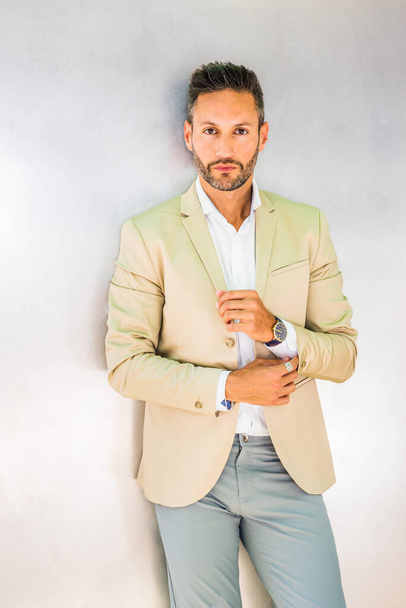 Portrait of Young Businessman in New York City. Young European Businessman with beard, wearing white shirt, beige jacket, standing against silver metal wall, hand touching cuff, looking forward - Foto, Imagem