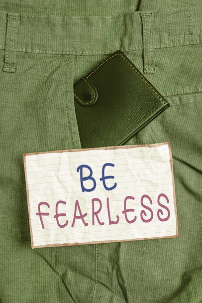 Text sign showing Be Fearless. Conceptual photo act of living in spite of those things that scare you to death Small little wallet inside man trousers front pocket near notation paper. - Photo, Image
