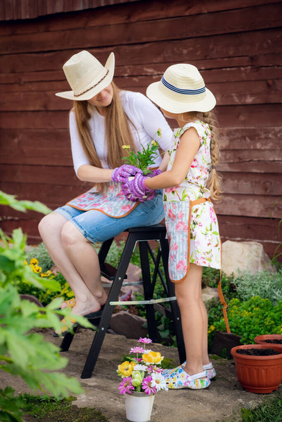 Bahçıvanlık, çiftçilik, anne-kız çiçek saksısına çiçek ekme. - Fotoğraf, Görsel