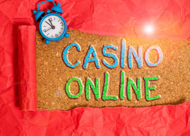 Teksti merkki osoittaa Casino Online. Käsitteellinen kuva pelaajille voi pelata ja lyödä vetoa kasinopelejä kautta verkossa herätyskello ja revitty pahvi yläpuolella puinen klassinen pöytä tausta
. - Valokuva, kuva