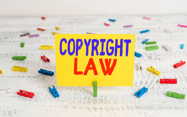 Conceptual hand writing showing Copyright Law. Business photo showcasing body of law that governs the original works of authorship Green clothepin white wood background reminder office supply. - Foto, imagen