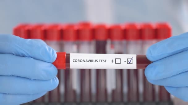 Laboratory assistant wearing protection gloves holds vial with negative coronavirus test - Felvétel, videó