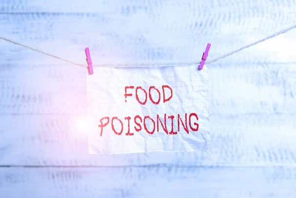 Kézírásos szöveg ételmérgezésről. Fogalom jelentése a betegség által okozott baktériumok vagy más toxinok az élelmiszerben Ruhaszárító téglalap alakú papír emlékeztető fehér fa íróasztal. - Fotó, kép