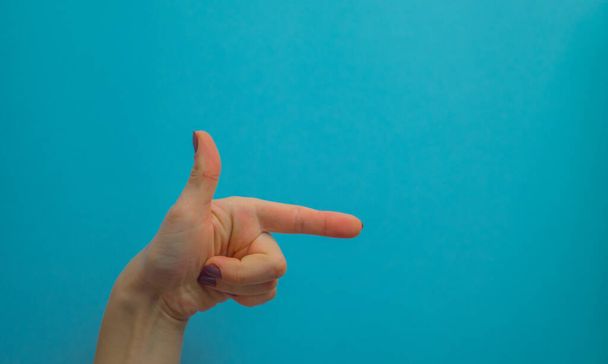 Les mains de la femme montrent des symboles et des gestes. gestes avec les mains isolées sur fond bleu. espace de copie
 - Photo, image