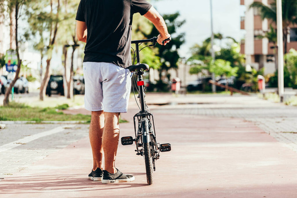 Young man pushing his folding bicycle outdoors - 写真・画像