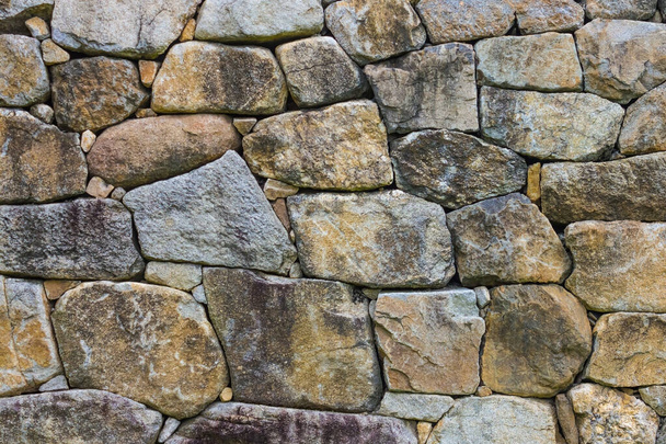 Μεγάλες πλακόστρωτες πέτρες διαφόρων σχημάτων. Σκληρές, ακατέργαστες πέτρες. Αρχαία τοιχοποιία. - Φωτογραφία, εικόνα