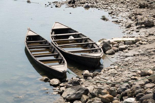 Two rowboats tied to a tree along the bank of a river. - Photo, Image