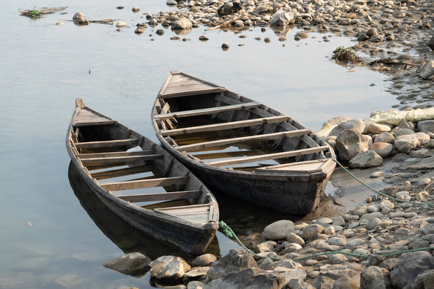 Two rowboats tied to a tree along the bank of a river. - Photo, Image