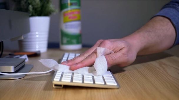 Homem limpa teclado do computador usando desinfetante Wipe
 - Foto, Imagem
