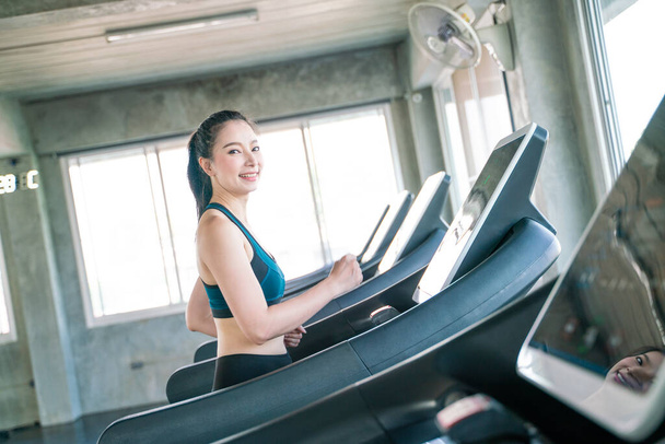 Inteligente asiático las mujeres corriendo en cinta de correr en moderno gimnasio de entrenamiento - Foto, Imagen