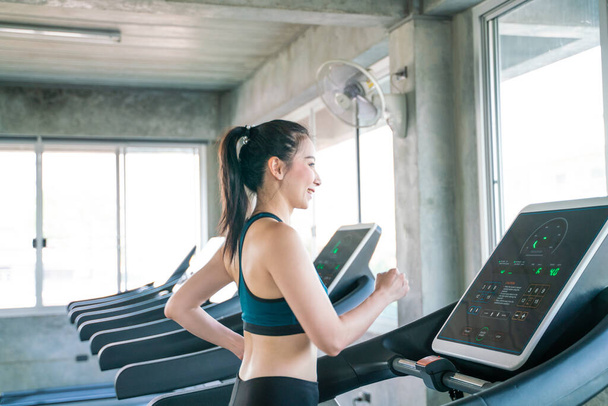 Smart asian women running on treadmill in modern gym working out - Photo, Image