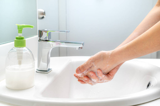 Donna che si lava le mani con sapone al lavandino per una buona igiene e per prevenire il virus covid-19
 - Foto, immagini