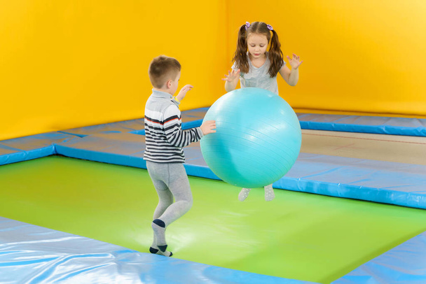 Happy smiling small kids jumping on indoors trampoline in entertainment center - Фото, изображение