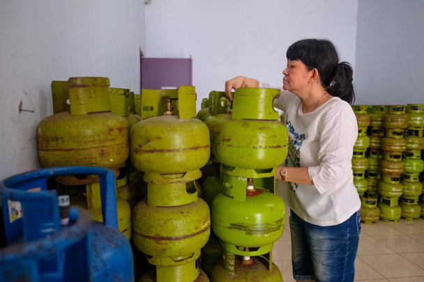 Femmes asiatiques indonésiennes arrangeant des bouteilles de gaz de 3Kg à l'intérieur d'un petit magasin familial local, ou appelé localement warung. La traduction du texte est "seulement pour les pauvres". Focus sélectif
. - Photo, image