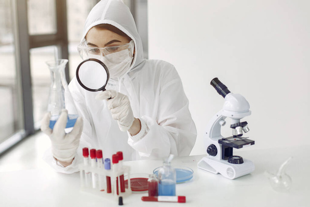 A laboratory scientist is examining blue solution in a bottle - Fotó, kép