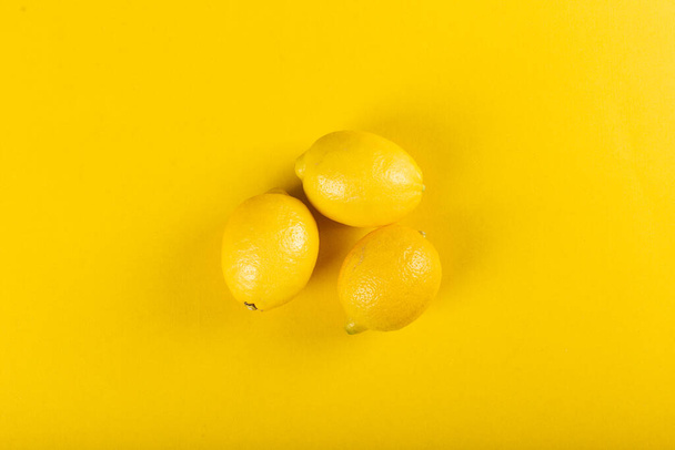 Yellow lemons on a yellow background. top view - Фото, зображення
