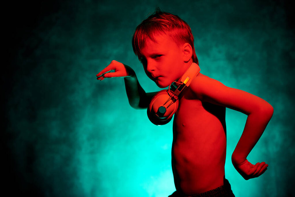 Rapaz de 8 anos com auscultadores ouve música e dança
 - Foto, Imagem