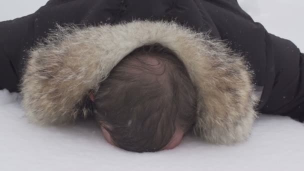 un homme couché dans la neige, face contre terre, au ralenti
 - Séquence, vidéo
