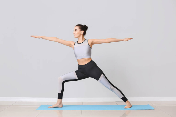 Giovane donna che pratica yoga vicino alla parete luminosa
 - Foto, immagini