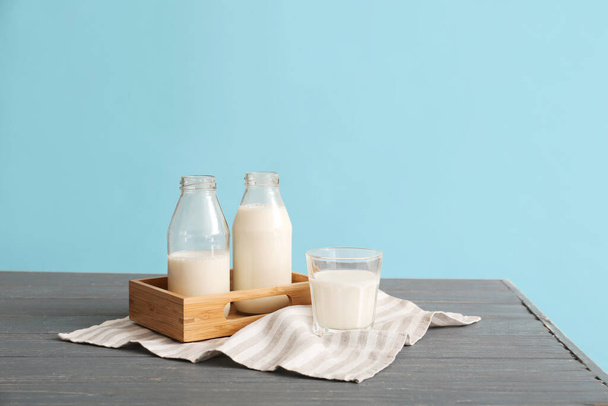 Gläser mit frischer Milch auf dem Tisch vor farbigem Hintergrund - Foto, Bild