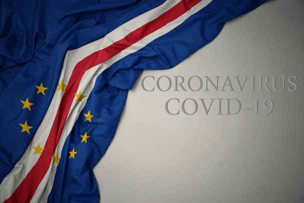 waving colorful national flag of cape verde on a gray background with text coronavirus covid-19 . concept. - Photo, Image