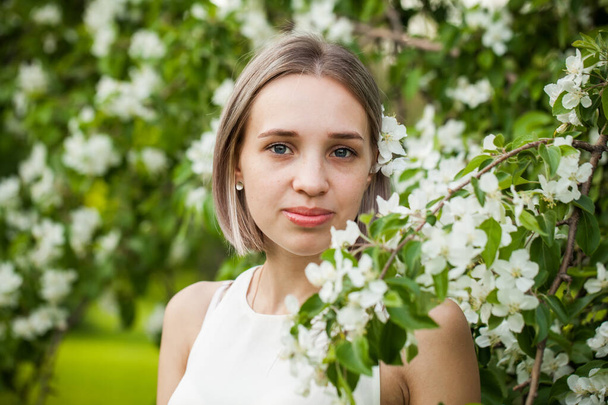 Cheerful girl with flowers in spring park - Фото, изображение