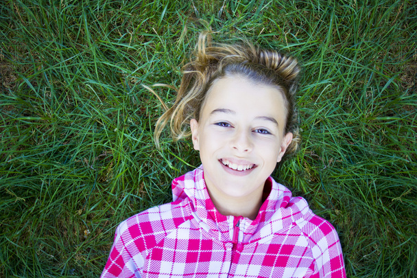 Girl lying on grass looking at camera - Photo, Image