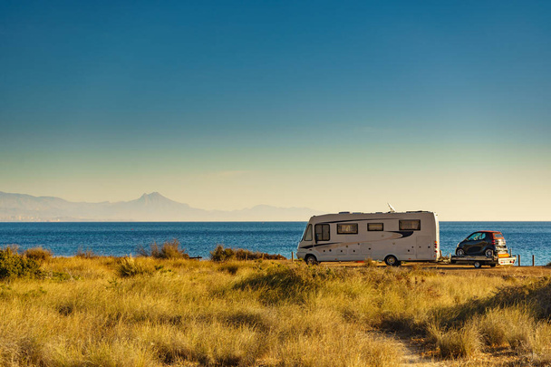 Camper on sea coast with with little car on platform, Spain. Camping on nature beach. Holidays and traveling in motor home. - Zdjęcie, obraz