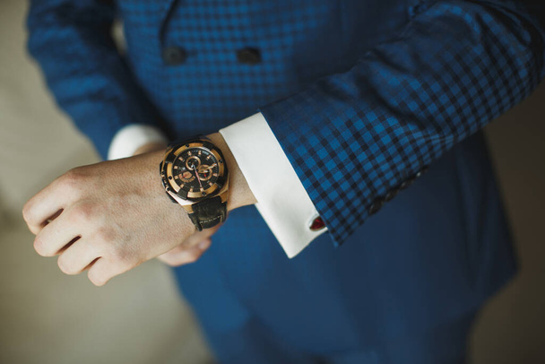 A businessman in a blue suit checks the time with his watch . - Фото, изображение