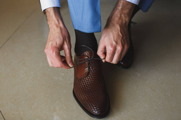 男の手は彼の新しい靴の靴ひもを結ぶ。人、ビジネス、ファッション、履物の概念-人の足と手の靴のレースを結ぶのを閉じる. - 写真・画像