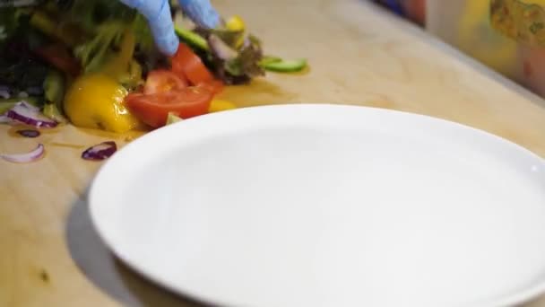 A férfi zöldségeket kevert és salátát tett egy fehér tányérra. - Felvétel, videó