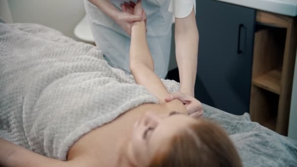 Massage - Masseurin massiert die Hände einer Frau, die mit spezieller Massagetechnik auf einem Sofa liegt - Filmmaterial, Video