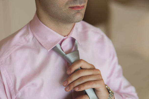 Un jeune homme d'affaires ajuste sa cravate grise
. - Photo, image
