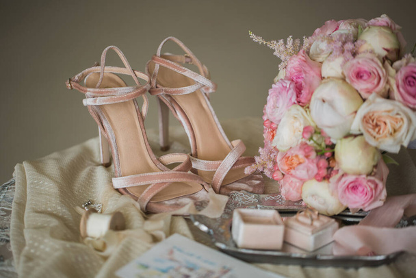 Μπεζ παπούτσια της νύφης, δαχτυλίδια και ένα μπουκέτο λουλούδια - Φωτογραφία, εικόνα