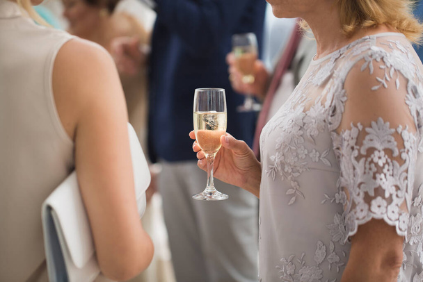 Glass of champagne on the background of a friends wedding in the hands of women. - Foto, afbeelding