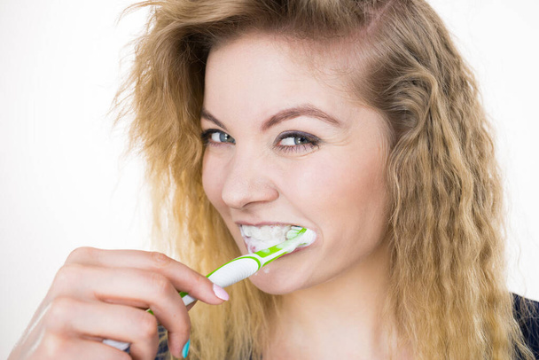Mujer cepillándose los dientes. Chica positiva con cepillo de dientes. Higiene oral. Estudio sobre fondo blanco - Foto, imagen