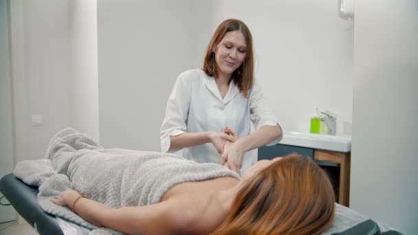 Massaggio - il massaggiatore sta impastando il polso di una donna giovane e dai capelli rossi
 - Filmati, video