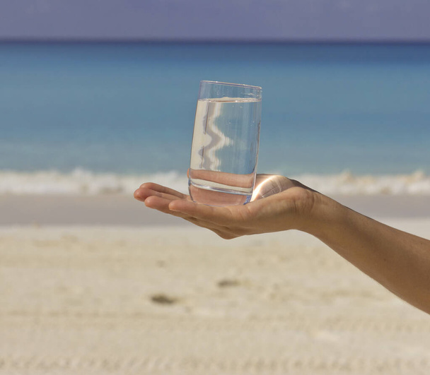 Un vaso de agua. Día de playa caliente. Un vaso de agua en manos femeninas. - Foto, Imagen