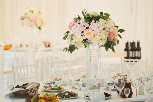 Ένα πανέμορφο μπουκέτο λουλούδια σε ένα βάζο στο τραπέζι του γάμου. - Φωτογραφία, εικόνα