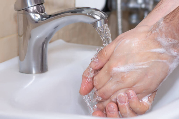 Um homem lava as mãos debaixo de água corrente. Fotografia de perto. Conceito de saúde, limpeza e higiene
. - Foto, Imagem