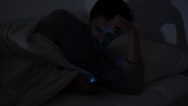 Joven en la cama por la noche utiliza un teléfono inteligente. Insomnio y dependencia digital, la chica en la cama
 - Imágenes, Vídeo