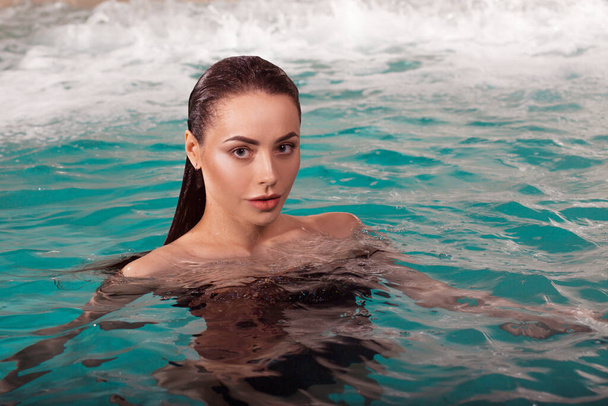 Beautiful young woman swimming in the pool, portrait. Attractive brunette girl - 写真・画像